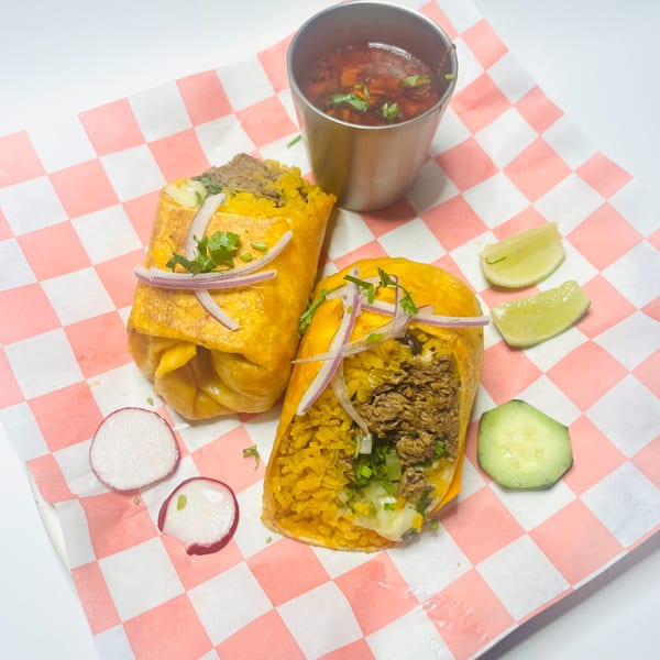 Two Mister Taco burritos with red onions, cilantro, rice, and meat, served with a side of consommé.
