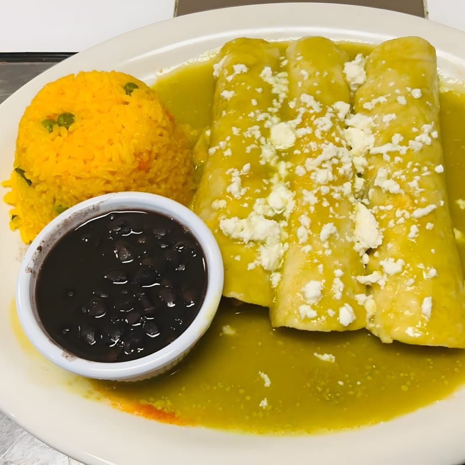 Three green enchiladas with crumbled cheese, yellow rice, and a side of black beans.